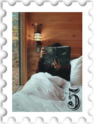 May 2021 Book By Its CoverSWG Challenge stamp - photo of a person sitting in bed reading a book with the cover obscuring their face
