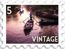 May 2022 Vintage SWG challenge stamp - A woman in a rice hat being rowed by a man in a boat. It is sunset and they appear to be leaving a floating market