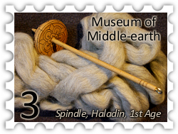 March 2018 Middle-earth Museum SWG challenge stamp - photo of a wooden drop spindle with flower embellishment on a bed of carded wool labelled "Spindle, Haladin, 1st Age"