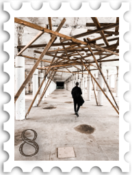 August 2022 Restoration and Rebuilding SWG challenge stamp - color photo of a person walking through a parking garage with chaotic wooden bracing augmenting the structure