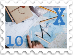 October 2022 X Marks the Spot SWG challenge stamp - color photo of a map, with a notebook, pencils, and tools for charting on top of it; a hand points to a particular location on the map