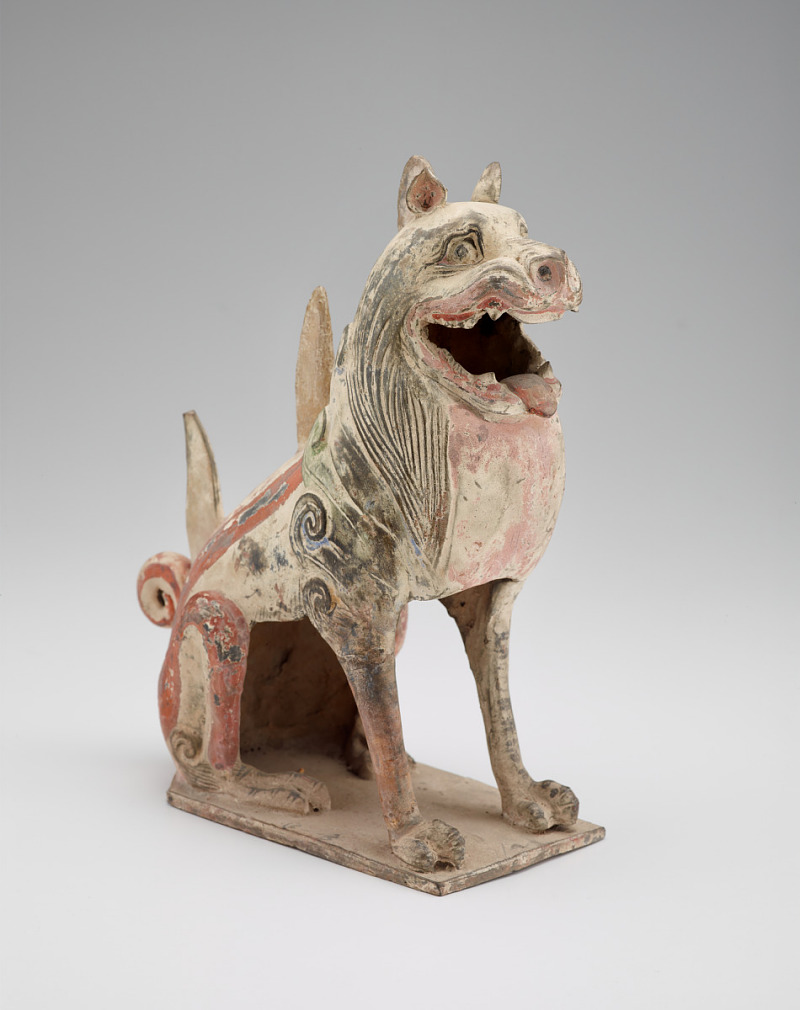 statue of a dog-like animal sitting with upright ears and an open mouth