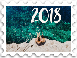 January 2025 Jubilee SWG challenge stamp - a photo of a couple sitting on a rock overlooking a sunlit green-blue sea, with the number "2018"
