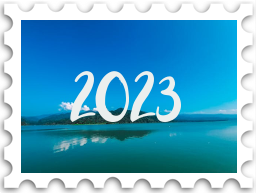 January 2025 Jubilee SWG challenge stamp - photo of a hill rising up above a lake or sea. The sky is bluer than the water, but only just The number "2023" is in the sky in white.