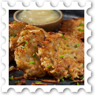 2024 Festival of Lights Commenter stamp - a closeup of scrumptious potato latkes  lightly sprinkled with chives; in the background is a dish of applesauce.