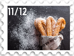 November/December 2025 Great Beleriand Bake-Off SWG challenge stamp - photo of churros dusted with confectioners' sugar. The churros are wrapped in newspaper, as if they've been bought from a street vendor.