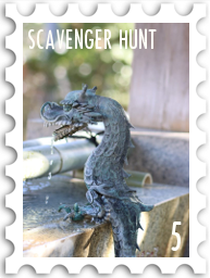 May 2026 Famous Scavenger Hunt SWG challenge  stamp - a color photo of a dragon fountainhead, with water running from its mouth into the angular stone basin of a fountain. The lighting and atmosphere suggest a nice spring or early summer day.