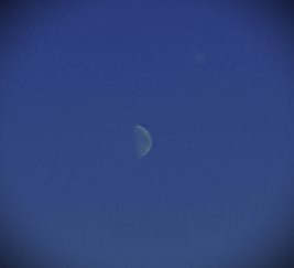 Photo of a quarter moon with a silver rim in a blue sky