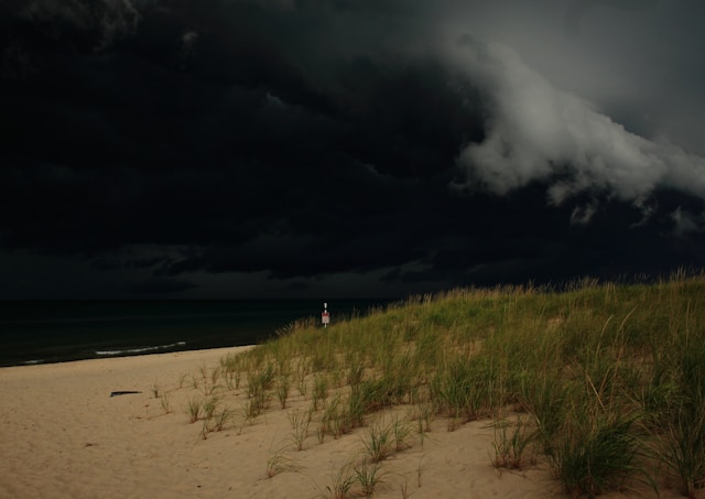 Photo of a ate summer storm on Lake Michigan: a sandy beach: the water appearing very dark under a stormy sky, with a menacing cloud in the right top corner