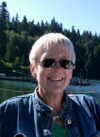 woman wearing denim jacket and sunglasses against backdrop of trees and water