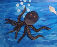 A black octopus in blue water emitting bubbles. There is a grey fish next to it. Acrylic paint on paper, cut out.