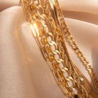An aesthetic picture of gold chains of varying sizes draped together in the sunlight.