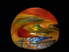 glass paperweight made by Grundy with swirling reds, oranges, yellows, and a bit of blue
